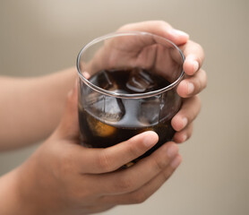hand is holding a glass of coffee with ices on a white isolated background