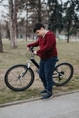 Fototapeta premium Joyful young kid staying active by cycling outdoors in a green park setting