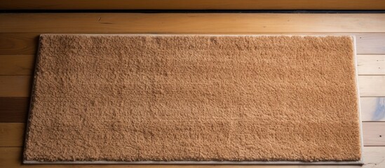 A black woolen bathroom rug placed on the wooden floor in front of a white door. The rug adds a touch of comfort and warmth to the bathroom setting.