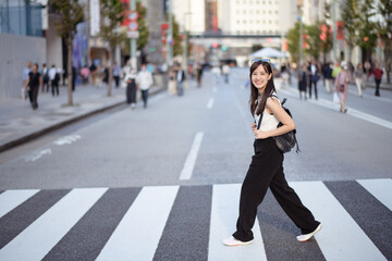 Amidst the crowd, a smiling Asian woman embraces the urban experience, blending fashion, happiness,...