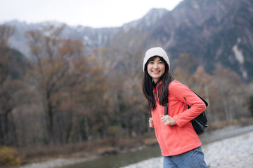 Joyful trek, Asian woman in a pink fleece explores Japan's scenic beauty. Hiking by the lake, an elegant portrait showcasing the achievement and excitement of the journey.