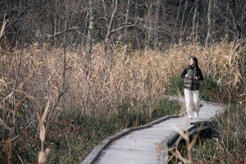 Tranquil trek: A young Asian woman explores a Japanese trail in fall, reveling in the vibrant...