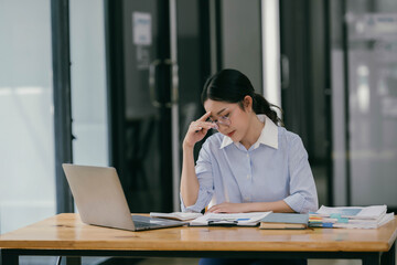 Asian women are stressed while working on laptop in her office room.