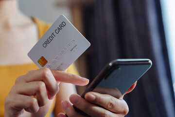 Girl holding credit card and using smartphone for shopping online with payment on internet banking.