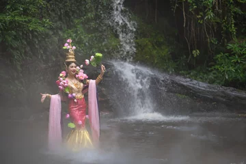 Fotobehang Thai traditional dress fashion show. Beautiful Asian woman portrait dressed in lotus flowers traditional Thai dress at the waterfall. © pomphotothailand
