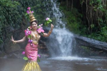 Tuinposter Thai traditional dress fashion show. Beautiful Asian woman portrait dressed in lotus flowers traditional Thai dress at the waterfall. © pomphotothailand