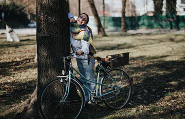 Obraz premium Cheerful young woman enjoying a sunny day in the park with her vintage bicycle.