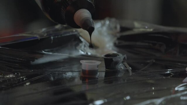 a tattoo artist puts drops of ink into a small container to load the iron or tattoo pen to avoid contamination