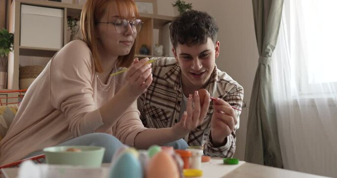 young man and woman couple or brother and sister paint easter eggs
