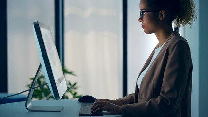 Black woman working with desktop computer in office.