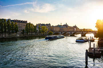 Beautiful Paris background at sunset showing Pont Royal Bridge, several cruise ships, and Orsay Museum at the background