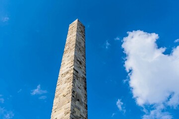Isolated view of a stone obelisk against the blue sky with wispy clouds, in Istanbul, Turkiye