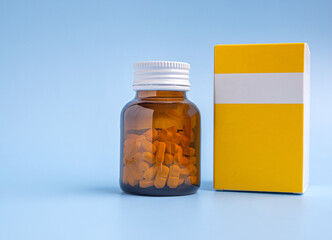 Yellow pill bottle and yellow pill box on blue background with copy space for text.