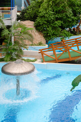 Water fountain in aquapark. Mushroom shape fountain in indoor adventure park full of green palm...