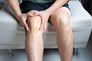 Man with knee pain, he puts his hand on his knee, pain point from osteoarthritis and...