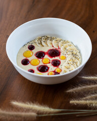 Oatmeal porridge in a bowl, served with berries and banana slices, healthy food for breakfast.