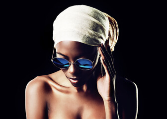 Black woman, sunglasses and headscarf with fashion for style on a dark studio background. Face of...