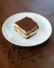 A piece of chocolate cake with white cream, sprinkled with chocolate chips on a plate, decorated with coffee beans.