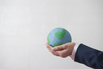 Woman's hand holding the globe, wearing a suit, white background