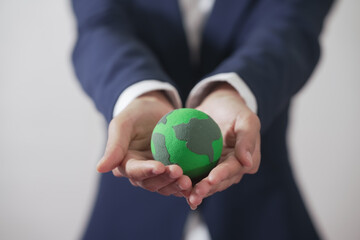 Woman's hand holding the globe, wearing a suit, white background