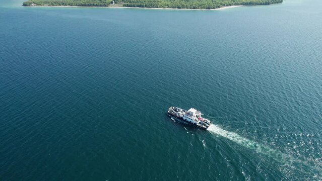 Drone view looking down on a ferry traveling with cars and people to an island