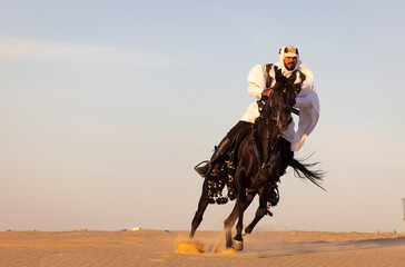 Saudi man in a desert with his black stallion