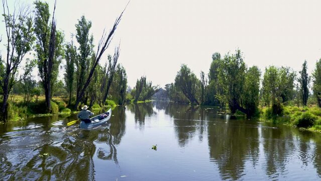 Man paddling a canoe on the canals of Xochimilco in Mexico City
