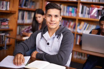 Young man, portrait or studying in library for test or scholarship on campus for class assignment....