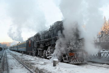 The locomotive has arrived at the railway station and is standing steam. View of a black retro train at Ruskeala station.