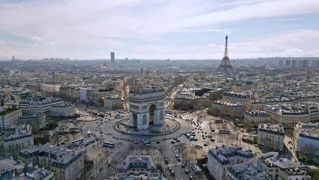 Triumphal arch or Arc de Triomphe with Tour Eiffel and Montparnasse tower in background, Paris cityscape, France. Aerial drone flyback