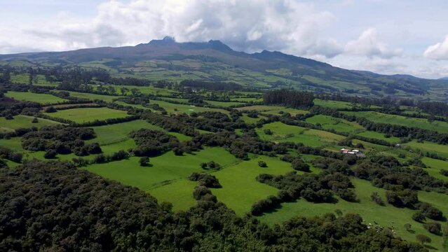 Cinematic drone clp flying up high over a large area covered with green and fields in Puichig, Equador