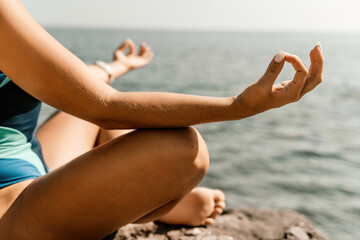 Yoga on the beach. A happy woman meditating in a yoga pose on the beach, surrounded by the ocean...