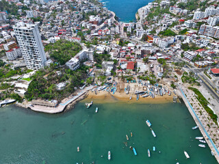 Expansive drone shot of Acapulco's Manzanillo Beach, showcasing its clear waters and surrounding urban landscape