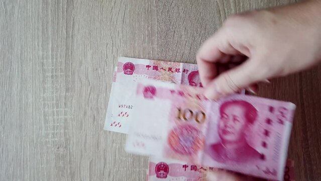 A woman is counting her money income. Close-up of hands with Chinese Yuan cash.