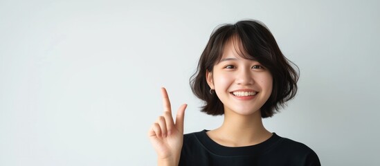 Asian short hair girl pointing finger on upper side with smile face on white background in studio. copyspace and presentation concept