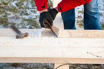 A man in a red jacket is engaged in construction using wooden planks