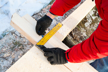 A man in a red jacket is engaged in construction using wooden planks - 755389346