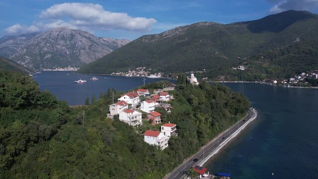 Kotor Bay, Montenegro, Drone Shot of Buildings and Church on Cape Above Sea and Ferry Line Boats in Kamenari