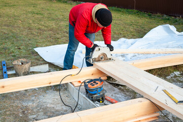 A man in a red jacket is engaged in construction using wooden planks - 755390539