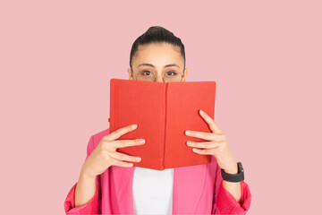 Woman hiding behind opened book, portrait of young brunette caucasian woman hiding behind opened...
