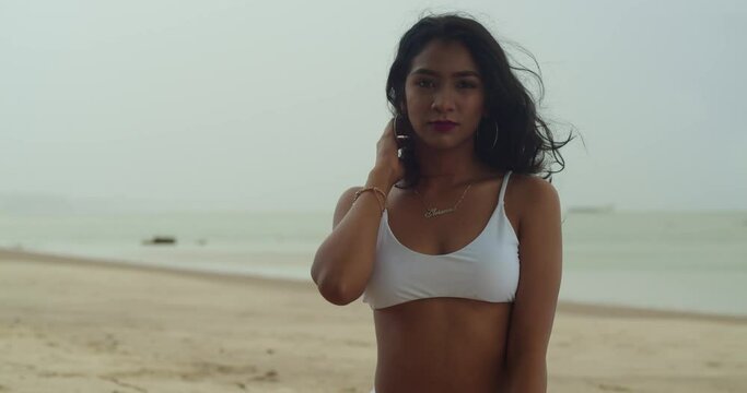 A woman in her youth, clad in a bikini, is delighting in a Caribbean tropical beach.