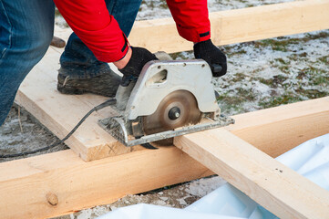 A man in a red jacket is engaged in construction using wooden planks - 755392165