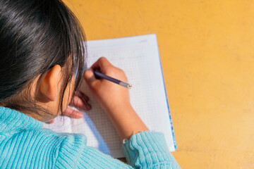 latina girl writing with a pencil on a piece of paper - education concept