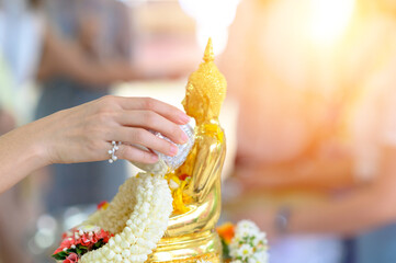 Songkran festival, Thai New Year. female hand holding silver bowl pouring water with jasmine and...