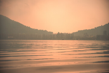 Misty Dal lake in Srinagar on the afternoon of January in Jammu and Kashmir. Still water with bare...