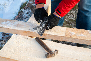 A man in a red jacket is engaged in construction using wooden planks - 755396742