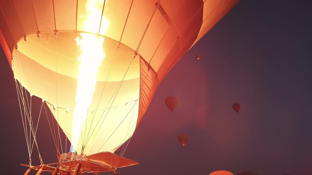 Launch of a large hot air balloon, close-up, with the flames filling it with hot air at dawn during twilight.