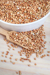 De hulled buckwheat with scoop on light wooden surface, top view