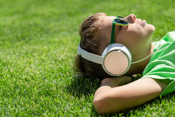 A boy relaxing on grass, listening to music - 755400791