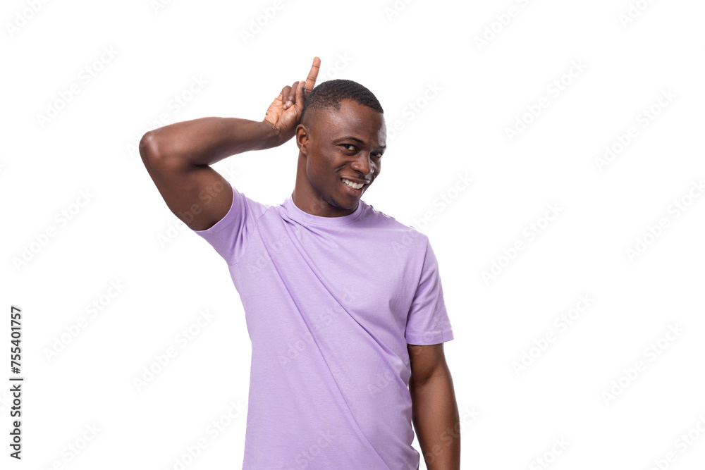 Wall mural a young authentic american guy dressed in a light lilac t-shirt is confident in himself on a white background